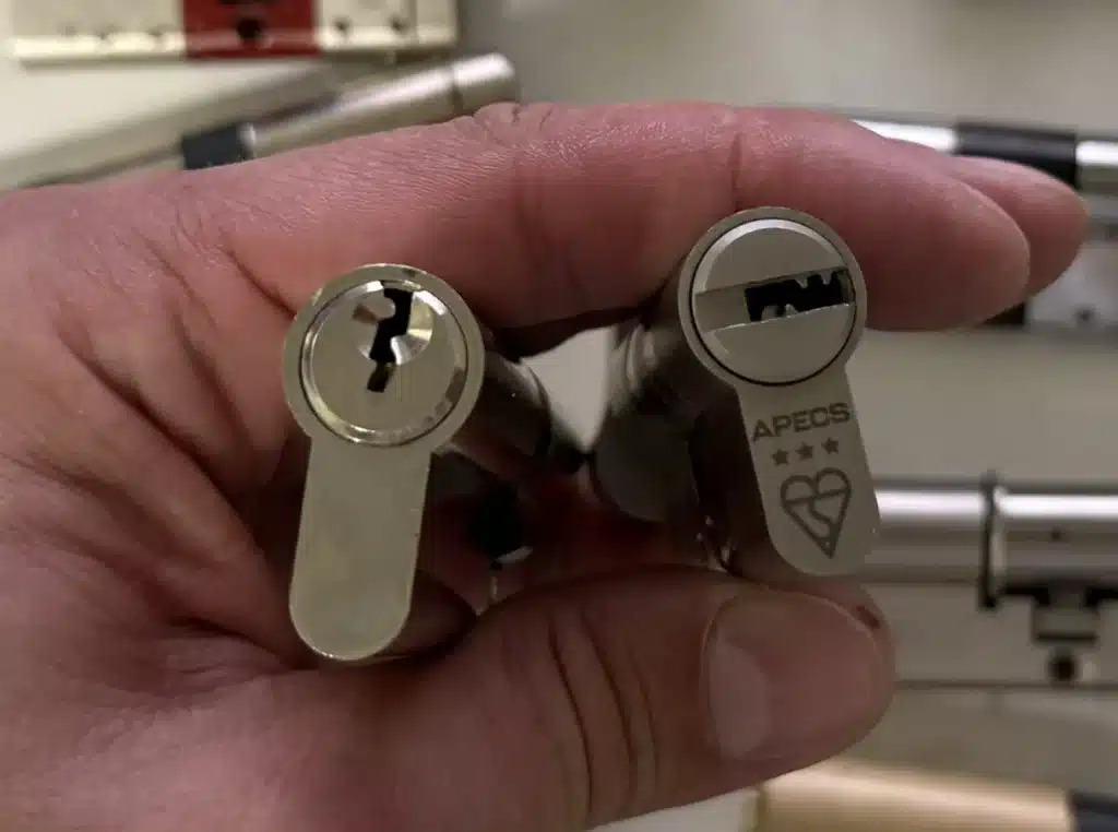 A 3-star Kitemark euro cylinder held next to an unrated cylinder, showing the three stars and BSI Kitemark stamp