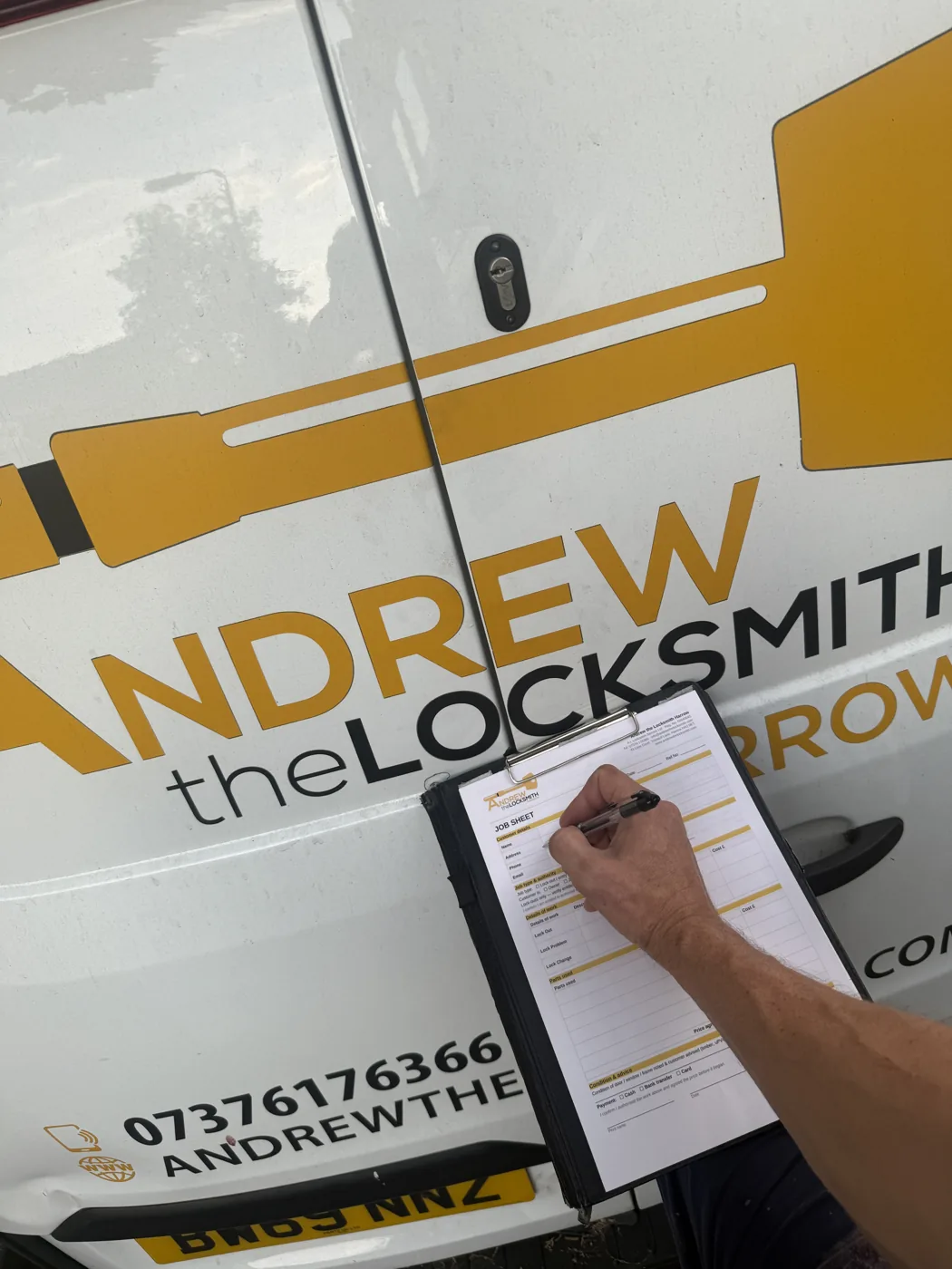 Andrew writing the agreed price on a job sheet against his Harrow locksmith van before starting work