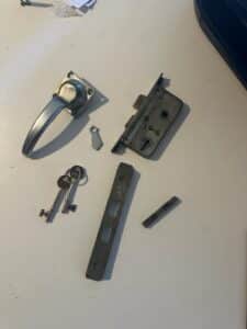 Lock case, lever handle, forend and spindle from an aluminium balcony door, repaired and rekeyed instead of replaced